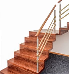 Da diese gerade Faltwerktreppe als Podesttreppe gebaut ist, kann sie sich förmlich in die Ecke des Wohnraums schmiegen. Die dunkle Holzfarbe bietet einen schönen Kontrast zu den Farben der Wände und unterstreicht perfekt die Faltung der Treppe. Auch das dezent moderne Geländer harmoniert vollkommen mit dem Charakter dieser Faltwerktreppe.